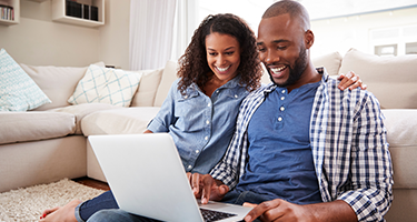 Couple sitting on couch looking at laptop