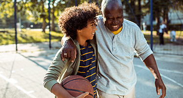 mature man playing basketball with grandson